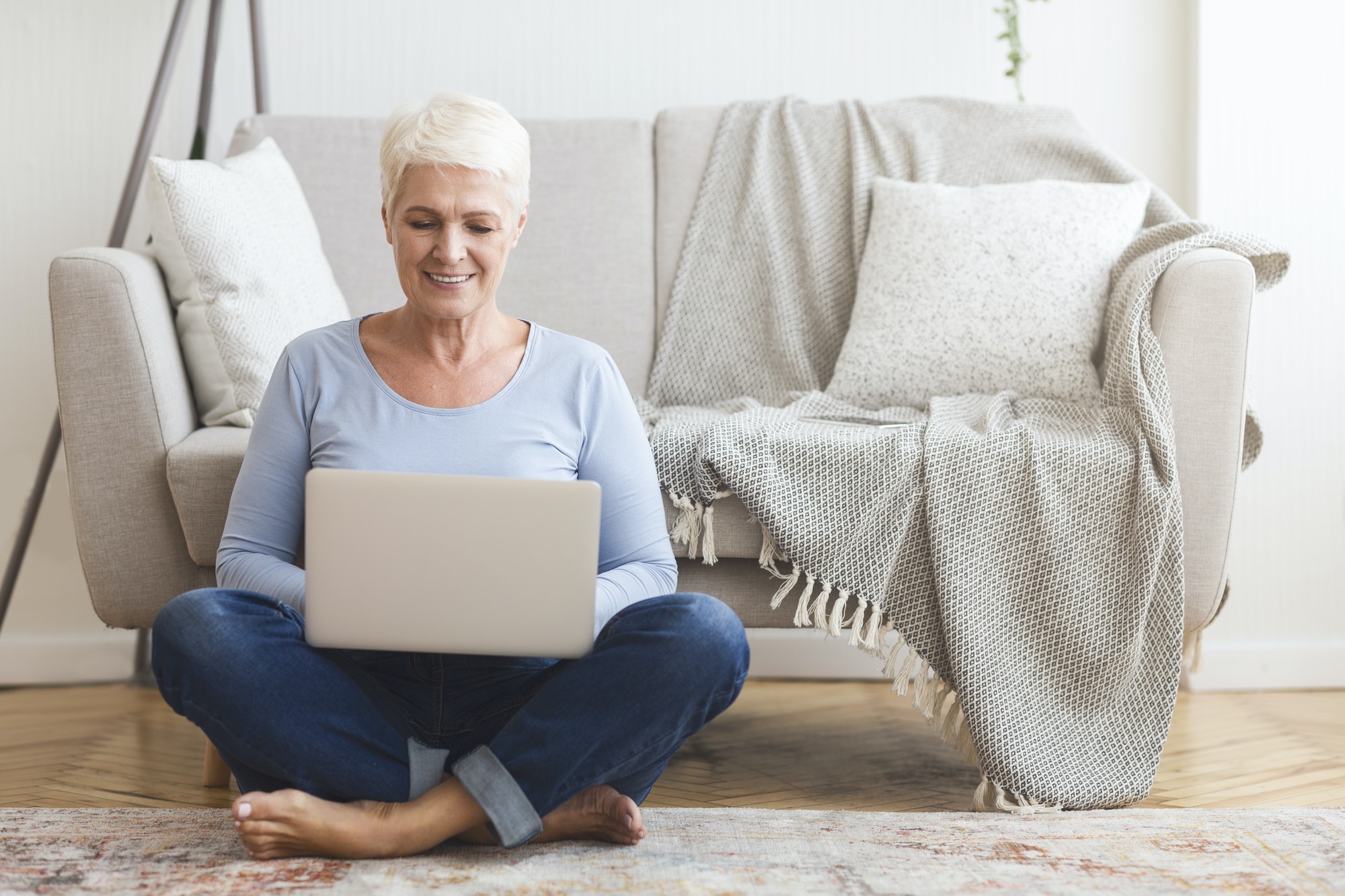 Resourceful mature woman sitting on floor and using laptop